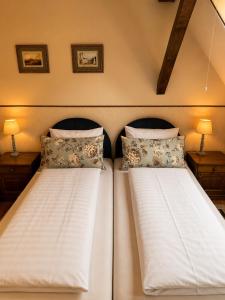 two twin beds in a room with two lamps at Kastélykert Vendégház in Bózsva