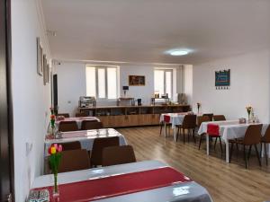 a dining room with tables and chairs and a kitchen at Archa Hotel Kochkor in Kochkorka