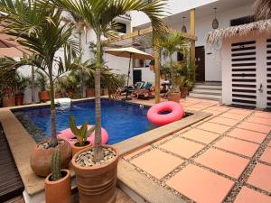 a swimming pool with palm trees and pink frisbees at Punta Kai Hotel & Hostal in Puerto Escondido