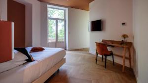 a bedroom with a bed and a desk and a window at La Villa Kara in Romans-sur-Isère