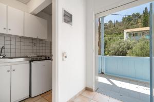 a kitchen with white cabinets and a large window at Villa Milia 2 in Agios Nikitas