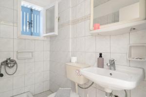 a white bathroom with a toilet and a sink at Villa Milia 2 in Agios Nikitas