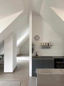 a white kitchen with a sink and a clock on the wall at Flösserhaus Steyr - Wohnen am Fluss in Steyr