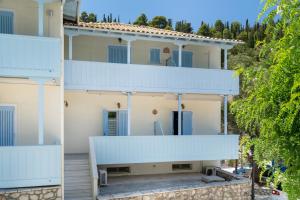 a building with white balconies and trees at Villa Milia 2 in Agios Nikitas