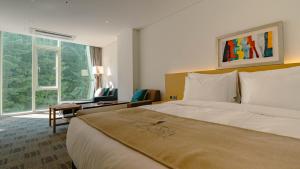a hotel room with a large bed and a window at Potalaka Naksan Beach Wellness in Yangyang