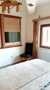 a bedroom with a bed and a chair and a window at Mersu Ala Konak Otel maşukiye sapanca in Kocaeli