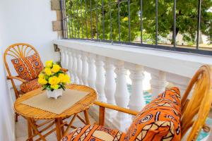 a balcony with chairs and a table with a vase of flowers at Bamburi BnB in Mombasa