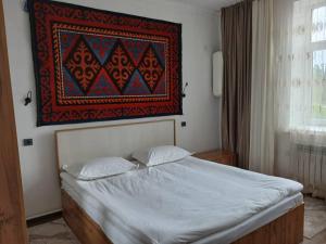 a bed with two pillows and a painting on the wall at Archa Hotel Kochkor in Kochkorka