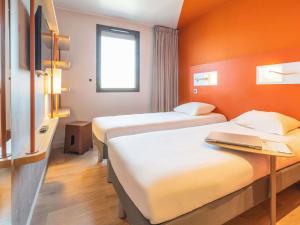 a hotel room with two beds and a laptop on a desk at ibis budget Rennes Rte Lorient in Rennes