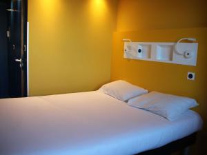 a bed with two pillows on it in a room at ibis budget Rennes Rte Lorient in Rennes +73 photos