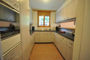 eine große Küche mit weißen Schränken und einem Fenster in der Unterkunft Luxury Family Apartment in Lauterbrunnen