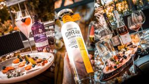 a person holding a bottle of wine and a plate of food at Hotel Tihany Átrium in Tihany