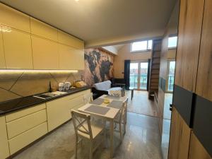 a kitchen with a table and a dining room at Apartament Na Wspólnej in Łeba