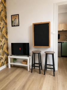 a living room with two stools and a flat screen tv at Les Sources Vichy in Vichy