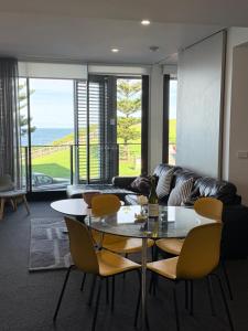 a living room with a glass table and yellow chairs at Newcastle Beach Escape in Newcastle