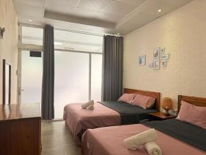 a hotel room with two beds and a window at Côn Đảo Home in Con Dao