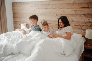 a woman and two children sitting on a bed at Šport Hotel *** Donovaly in Donovaly