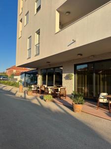 a building with tables and benches in front of it at Aurum Apartmanı in Vodice
