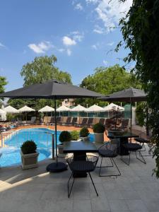 a patio with tables and umbrellas next to a pool at Atlantic Hotel - Free Parking in Sofia