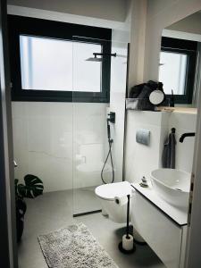 a white bathroom with a toilet and a sink at Olympus Pearl in Skotina +37 photos