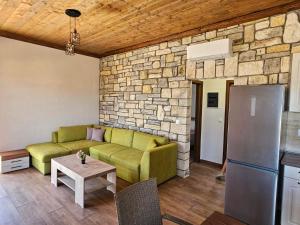 a living room with a green couch and a stone wall at Alyki Stone House 2 in Alyki