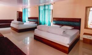 two beds in a room with blue curtains at Hotel Chandra Lok Cottage Kabra Niketan in Gangotri