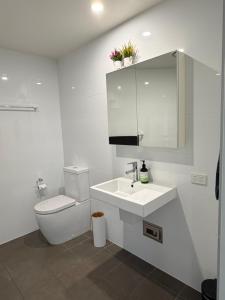 a white bathroom with a toilet and a sink at Newcastle Beach Escape in Newcastle +24 photos