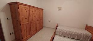 a bedroom with a wooden cabinet and a bed at Alloggio Ziu Oreddu in Orgosolo