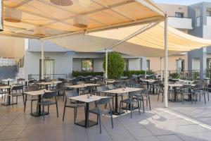 an outdoor patio with tables and chairs under a canopy at Sunrise Village Hotel - All Inclusive in Platanias