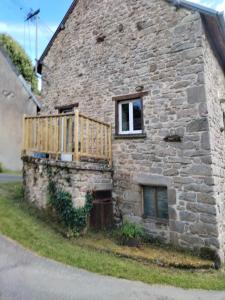 a stone house with a wooden balcony on the side of it at La maison d'André in Laurière