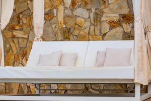 a white bench with pillows in front of a stone wall at Playitas Hotel - Sports Resort in Las Playitas