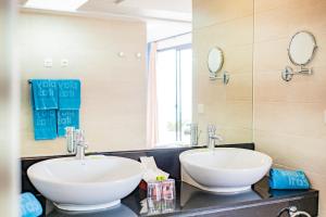 two sinks in a bathroom with two mirrors at Playitas Hotel - Sports Resort in Las Playitas