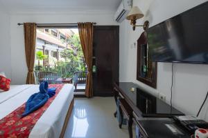 a bedroom with a bed and a flat screen tv at Taman Ayu Legian Hotel in Legian