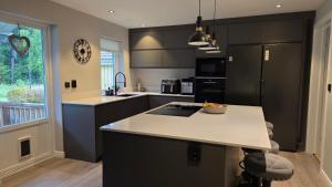 a kitchen with black cabinets and a white counter top at Modern cosy house with forest views in Södertälje +8 photos