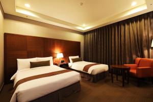 a hotel room with two beds and a chair at Bridge Hotel Incheon Songdo in Incheon
