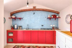 a kitchen with red cabinets and a blue wall at Casa Vacanze Panoramics in Acquedolci +54 photos