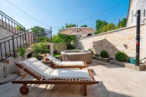 a patio with two lounge chairs and an umbrella at House Bany in Skradin