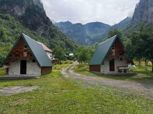 two small buildings in a field with mountains in the background at Guesthouse Stanisic in Dobrilovina