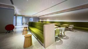 a room with a green couch and tables and chairs at JI Hotel Beijing Huilongguan in Changping