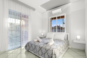 a bedroom with a bed with white walls and windows at Minimal Stay House in Petalidi