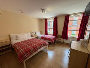 a bedroom with a bed and a desk and two windows at Seven Dials Hotel in London
