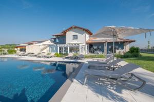 a house with a swimming pool with chairs and an umbrella at Villa Sarmassa in Narzole