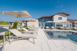a swimming pool with chairs and an umbrella next to a house at Villa Sarmassa in Narzole