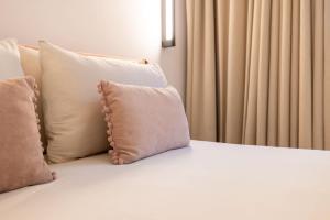 a bed with two pillows sitting next to a window at The Homega Villa in Il-Madliena