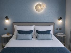 a bedroom with a large bed with blue pillows at Boutique Hotel Alassio in Alassio