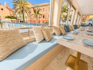 a row of tables in a restaurant with palm trees at Boutique Hotel Alassio in Alassio