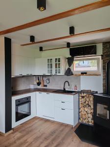 a kitchen with white cabinets and a stone wall at Chalet Zasavka in Dol pri Hrastniku