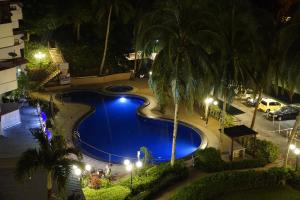 una piscina blu con palme di notte di Sri Sayang by Coral Holiday Resort a Batu Ferringhi