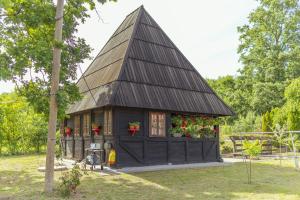 a small house with a gambrel roof with flowers at Brvnara Jez in Kraljevo +11 photos