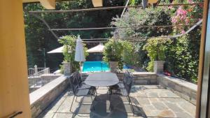 a patio with a table and chairs and a pool at Chalet al Lac - Cuori - Swimming Pool Como Lake View in Consiglio di Rumo